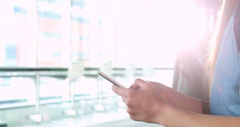 Young Woman Engaging with Smartphone in Bright Modern Space - Download Free Stock Images Pikwizard.com