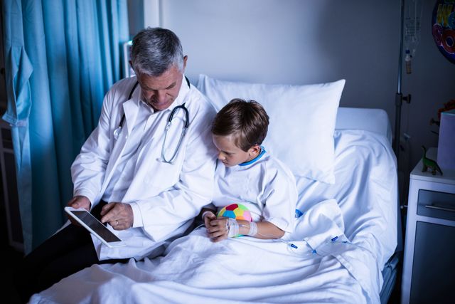 Doctor showing medical report to young patient in hospital bed. Ideal for use in healthcare, medical technology, pediatric care, and hospital-related content. Can be used in articles, blogs, and promotional materials focusing on patient care, medical consultations, and the use of technology in healthcare.