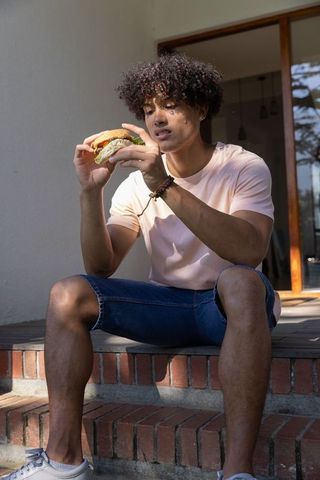 Young man enjoying casual outdoor meal on brick steps