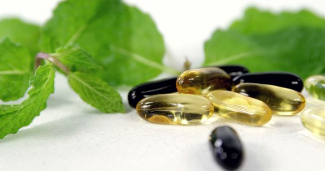 Fish oil supplements are scattered on a white surface, accompanied by fresh mint leaves in the background, emphasizing themes of health and wellness. This image can be used on blogs, health websites, and promotional materials for nutritional supplements.