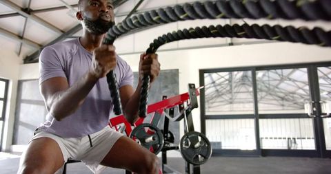 Athletic Man Engaging in Battle Rope Workout at Modern Gym