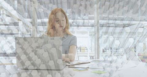 Redhead reviewing laptop and arranging sticky notes in bright modern office with geometric overlay