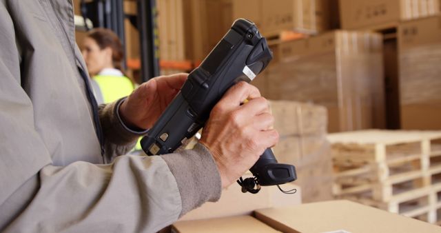 Warehouse worker scanning packages using a handheld device. Ideal for illustrating concepts related to logistics, shipping, inventory management, barcode scanning, warehouse operations, and supply chain management.