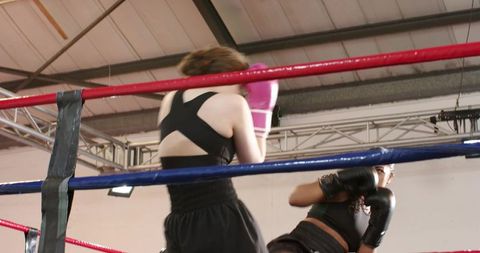 Female boxers trading jabs while referee signaling in gym ring
