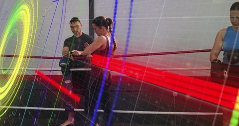 Coach wrapping female fighter hands in boxing ring with neon motion light overlays