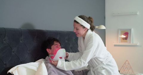 Couple applying led light therapy facial mask during cozy at-home skincare wellness night