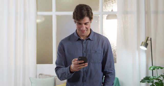 Young Man Smiling While Using Smartphone Indoors - Download Free Stock Images Pikwizard.com