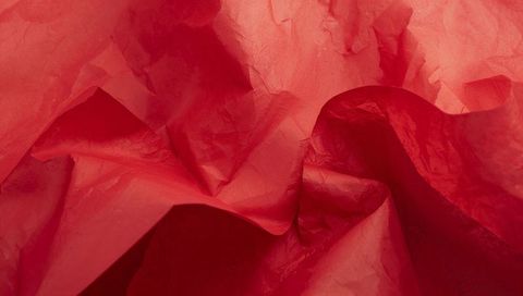 Crinkled red tissue paper abstract backdrop featuring dramatic folds and lit ridges