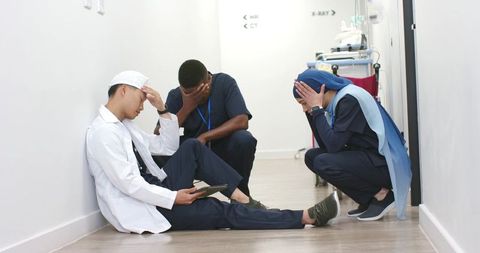 Multicultural medical team reacting to emergency in hospital corridor with tablet