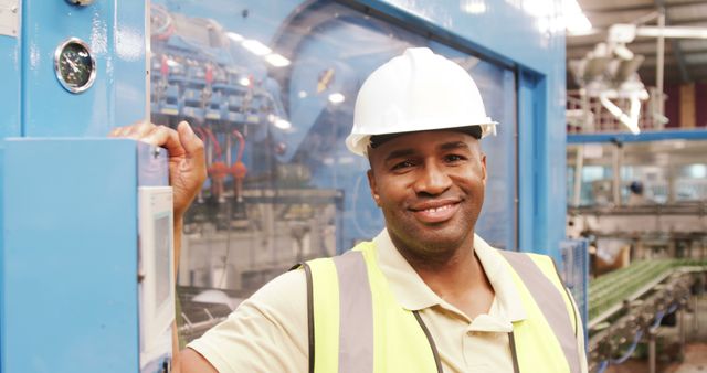 Smiling Factory Worker Wears Hard Hat and Safety Vest in Manufacturing Plant - Download Free Stock Images Pikwizard.com