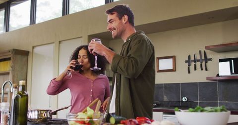 Couple Enjoying Wine While Preparing Meal in Cozy Kitchen