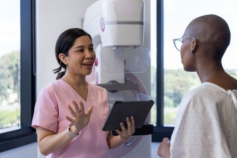 Radiology Technologist Explaining Mammogram to African American Woman at Mammography Unit