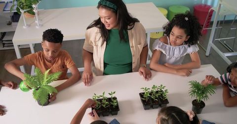 Teacher guiding diverse students planting seedlings in classroom gardening activity