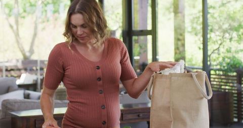 Expecting Mother Unpacking Groceries in Sunlit Kitchen
