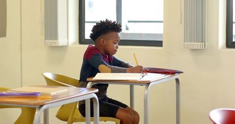 Focused Boy Writing in Classroom
