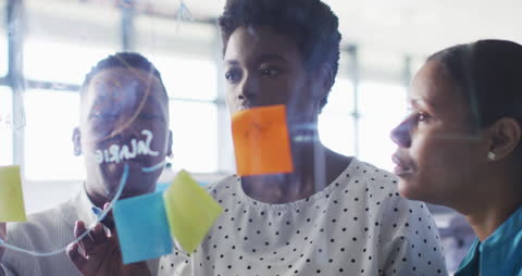 Team Collaborating Around Glass Board at Office