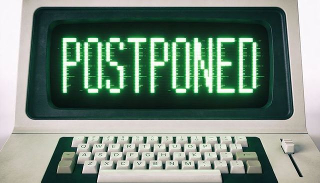 Retro computer terminal showing postponed on green crt display with keyboard closeup