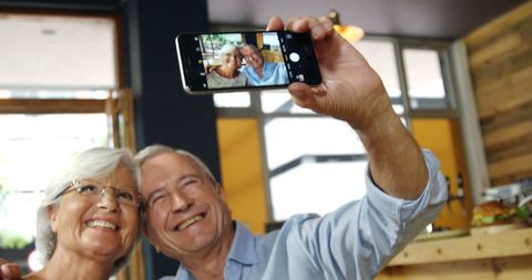 Senior Caucasian Couple Enjoying Selfie at Cozy Cafe