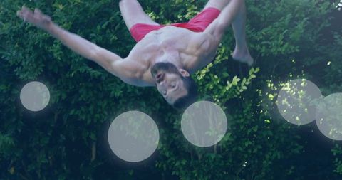 Man Performing Backflip in Yard with Red Swim Trunks