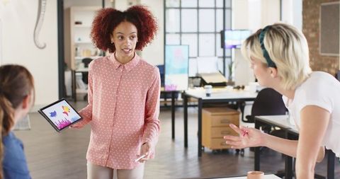 Diverse Female Team Collaborating with Tablet Graphics in Modern Office