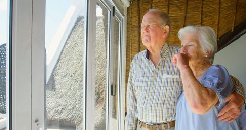 Senior Couple Gazing Out Window Embracing