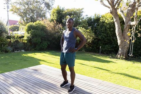 African american man standing on wooden deck in backyard wearing athletic gear and sneakers