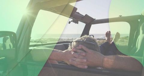 Reclining man relaxing in open suv at sunlit beach with feet on dashboard and sunglasses