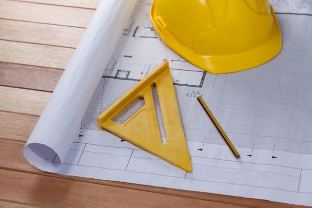 Architectural plan with tools and hard hat on wooden table