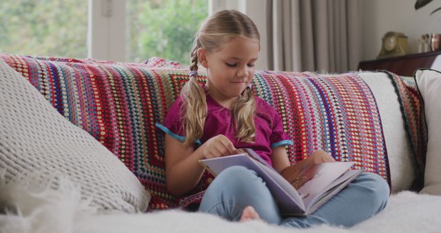 Young Girl Reading Book on Colorful Couch at Home - Download Free Stock Images Pikwizard.com