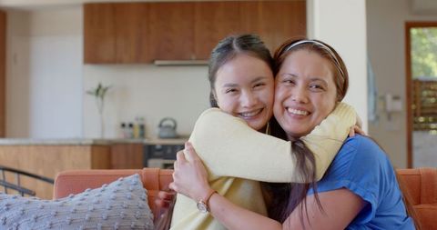 Smiling Mother and Daughter Embrace on Modern Living Room Sofa