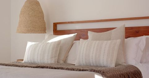Elegant minimalist bedroom with wooden bed and woven lamp