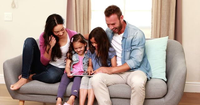 Happy Family of Four Enjoying Quality Time with Tablet in Living Room - Download Free Stock Images Pikwizard.com