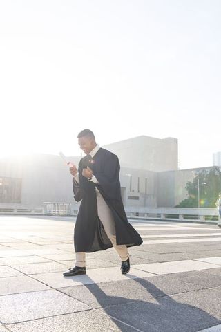 African american graduate striding across urban plaza celebrating diploma and future