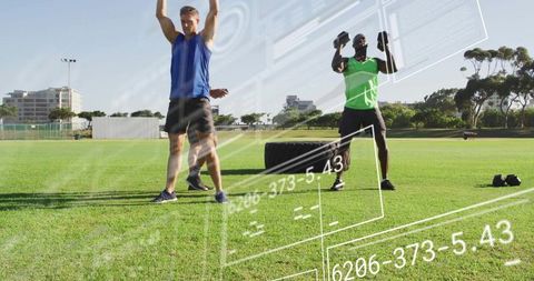 Performing outdoor functional fitness training two men lifting overhead with dumbbells near tire