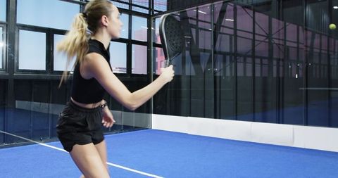 Female padel player hitting ball on indoor court