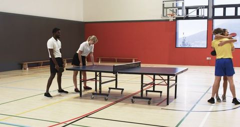 Friends Enjoying Ping Pong in Sports Hall with Energy and Sportsmanship