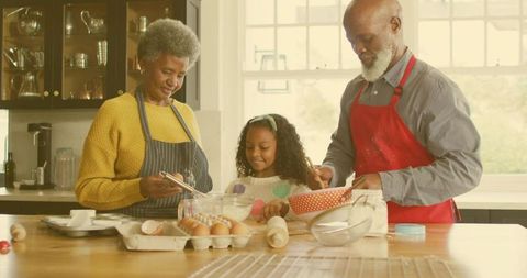 Grandparents Guiding Granddaughter Baking Together in Sunlit Kitchen at Island
