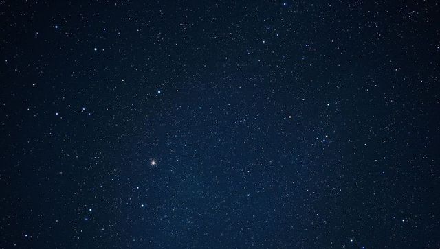 Night sky revealing dense starfield and faint milky way band with bright planet