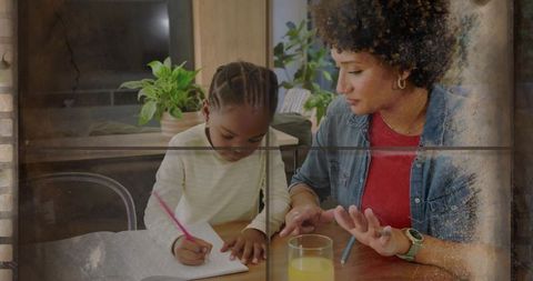 Mother helping daughter with homework at sunlit kitchen table, guiding writing and bonding
