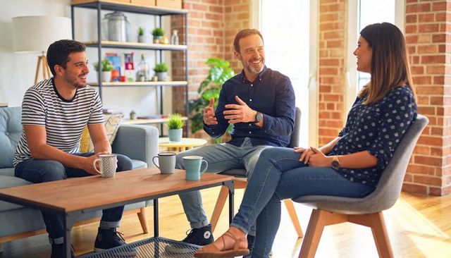 Sharing ideas and laughing in modern loft living room with brick wall and coffee mugs