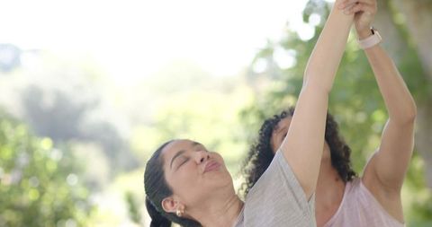 Two women stretching together outdoors celebrating fitness and wellness in sunlit park