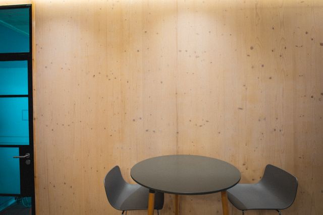 Empty chairs and table by wooden wall with copy space in creative office. creative business and office workplace.