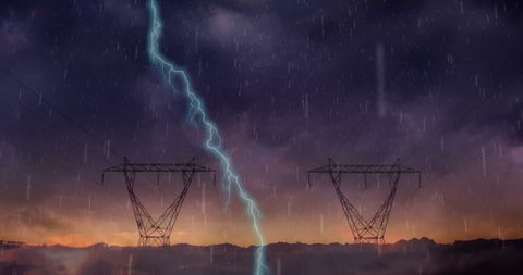 Electricity towers amidst dramatic thunderstorm at sunset