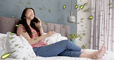 Serene woman reclining on bed talking on smartphone with glowing particle burst in bedroom