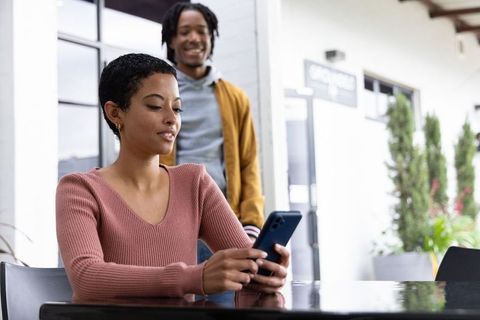 African american colleagues sharing smartphone in modern cafe workspace for collaboration