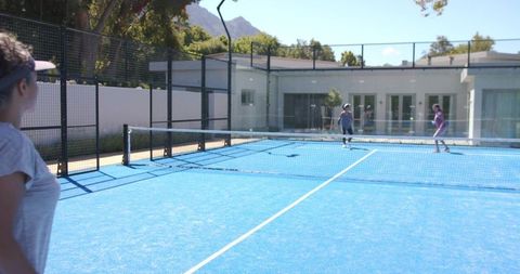 Woman watching pickleball match on vibrant blue outdoor court at clubhouse