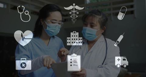 Masked clinicians collaborating over tablet in hospital ward with healthcare icons overlay