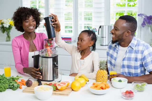 Family enjoying quality time making a healthy smoothie together in a bright, modern kitchen. Ideal for promoting family bonding, healthy eating habits, and lifestyle content. Can be used in advertisements for kitchen appliances, health and wellness campaigns, or family-oriented products.