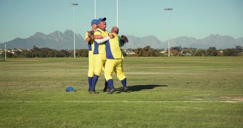 Diverse male cricketers celebrating victory on field wearing yellow blue uniforms