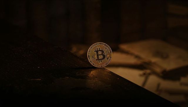Glowing Gold Bitcoin Standing on Edge of Dark Desk with Dusty Notebook, Cinematic Lighting